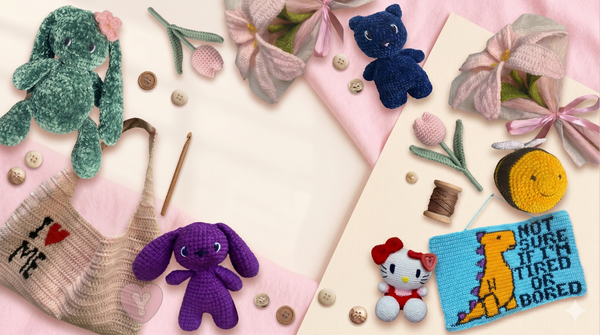 A styled flat-lay of handmade crochet and knit toys and accessories on a pink and cream background, including plush bunny figures in green and purple, a small Hello Kitty doll, a knitted dinosaur patch, thread, buttons, and fabric flowers.